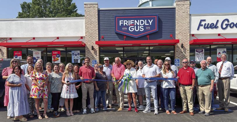 The owner of Friendly Gus, Guy Cochran (center), cuts the ribbon at the new store’s Aug. 11 grand opening.