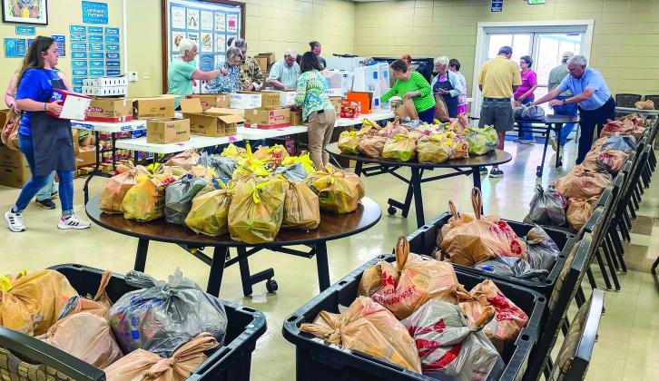 Volunteers with community ministries bag food, led by Hannah Foval (far left), to address access to food for students outside of the school day. CONTRIBUTED