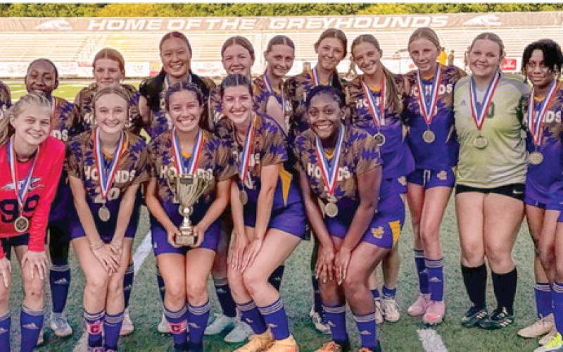 A championship trophy and medals in hand, the Lady Greyhounds proudly celebrate being crown region champs after Thursday’s non-region win against Bleckley County. BRAD HARRISON/Staff