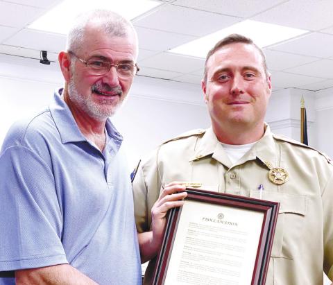 Board Chairman Chris Weidner (left) presents the Proclamation for Law Enforcement Appreciation Week to JCSO Capt. Travis Douglas. DEBBIE LURIE-SMITH/Staff mation for Law