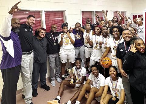 A first-place trophy and medals in hand, the Lady Greyhounds celebrate the region tournament championship on Friday at Woodland High School in Stockbridge. CONTRIBUTED