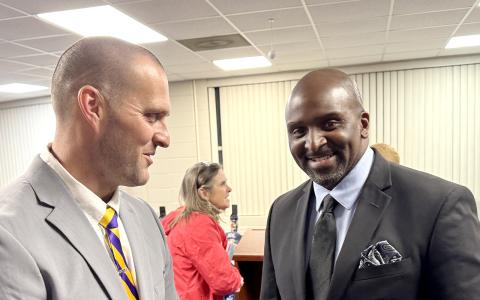 New JCHS head football coach Justin Montgomery speaks with principal Dennis Woolfolk during Tuesday's Board of Education meeting..