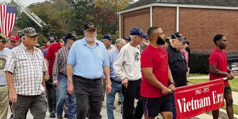 Veterans lined up under the big flag and marched into the W.E. Knox Center behind the banners of their conflicts at the Nov. 9 Veterans Appreciation Day Event.