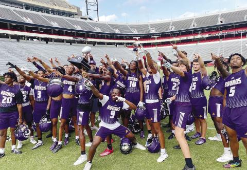 With a first-place trophy in hand, the Greyhounds celebrate Between The Hedges after winning last week’s 7-on-7 tournament at UGA. CONTRIBUTED