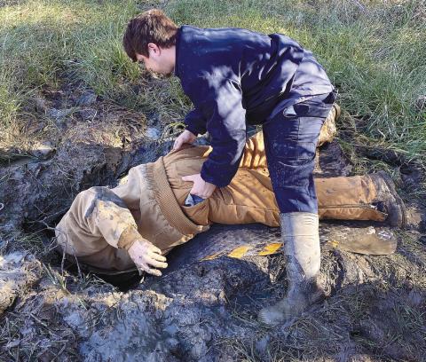Sheldon Hicks keeps Bobby Dixon from falling in the ditch while he works to repair a water leak. CONTRIBUTED