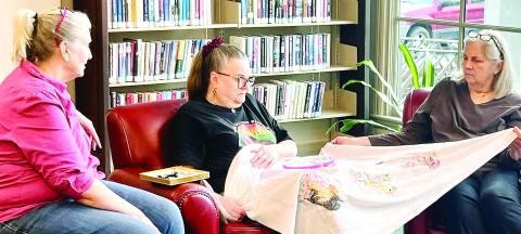 Three ladies in the group look at cross stitching as they talk during the session at the Jones County Library. CONTRIBUTED