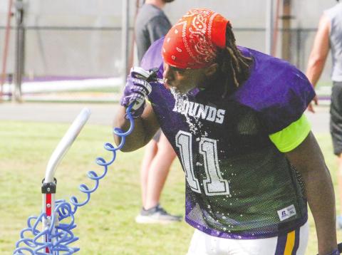 A Greyhounds football player takes a break to hydrate during practice earlier this year. Drinking plenty of water is among the keys to staying cool in the midst of high temperatures. BRAD HARRISON/Staff