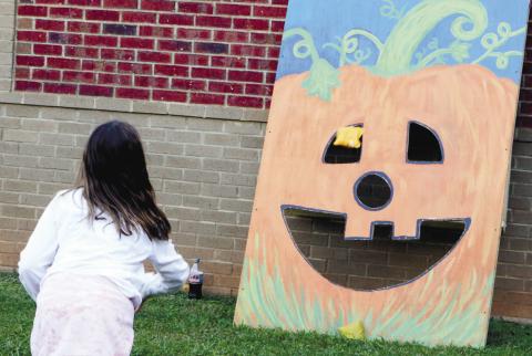 A student tosses a bean bag into a wooden cut out of a pumpkin during the Turner Woods Fall Festival. NATHAN CLARKE/Contributed