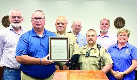 Jones County Commissioners surround Jones County Sheriff’s Office Chief Deputy Earl Humphries (front row holding proclamation), Deputy Al Elliot (center front) and Lt. Brent Skinner. DEBBIE LURIE-SMITH/Staff