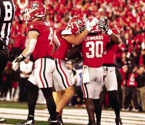 Running back Daijun Edwards (30) is congratulated by teammates after one of his rushing touchdowns. H ZAK ROBINSON PHOTOGRAPHY/Contributed e had two on the night.