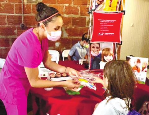 A member of the DPH oral health team gives out toothbrushes and toothpaste to students at the Back to School Bash.