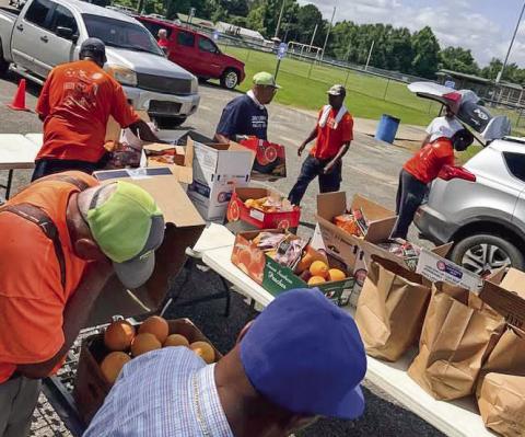 Volunteers at the monthly food distribution at the Highway 49 recreation center work in all weather. CONTRIBUTED