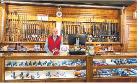 Store co-owner Chris Williams behind the county of Gray Station Firearms and Pawn. DEBBIE LURIE-SMITH/Staff
