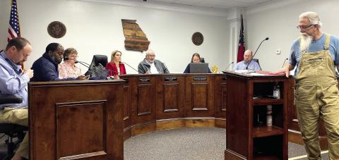Matt Simms (far right) presents a petition to the commissioners at their Dec. 3 meeting requesting removal of the Board of Assessors. DEBBIE LURIE-SMITH/Staff