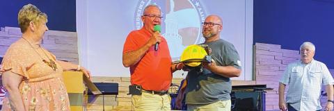 Karen McMichael watches as husband Glenn passes the helmet along with the position of Captain of Station 3 to his son, Jason, following his promotion.