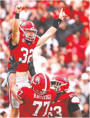 Georgia offensive lineman Tate Ratledge (77) holds up Cash Jones (32) after he scored a touchdown in the fourth quarter of the Bulldogs win over South Carolina last week. TONY WALSH/UGA Athletics