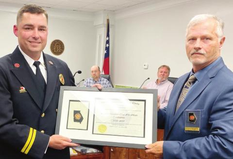 Tony Griffin (left) is awarded the Volunteer Fire Chief’s certification from Robert Singleterry with the Georgia Association of Chiefs at the April 26 meeting. DEBBIE LURIE-SMITH/Staff