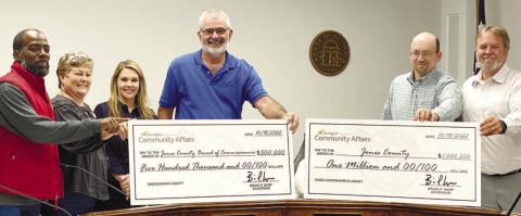 Near the end of the Nov. 1 Board of Commissioners meeting, Chairman Chris Weidner (center) presents checks for the county from the Georgia Department of Community Affairs. DEBBIE LURIE-SMITH/Staff