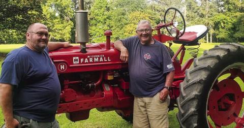 Brett McMichael (left) and father Glenn with one of their favorite pastimes, rebuilding Farmall tractors. CONTRIBUTED