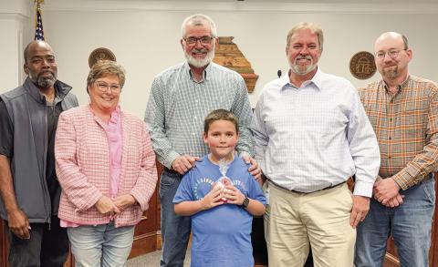 Commissioners surround 8-year-old Eli Altamirano, who led the opening prayer and pledge at their March 18 meeting. BETHANY TAPEE/Staff