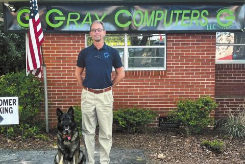 Joe Rutledge poses for a photo outside of Gray Computers with his loyal dog, Sebastian.