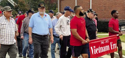 Veterans lined up under the big flag and marched into the W.E. Knox Center behind the banners of their conflicts at the Nov. 9. 2024 Veterans Appreciation Day Event. FILE PHOTO
