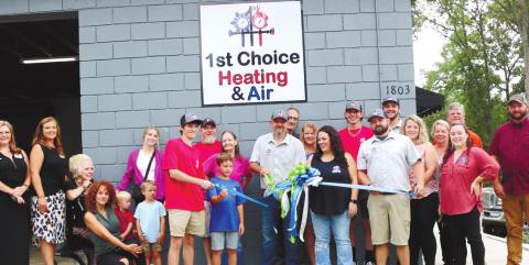 Michael Tidwell cuts the ribbon at the ribbon cutting ceremony for 1st Choice Heating &amp; Air with his employees, family and friends. ALAINA CLARKE/Staff