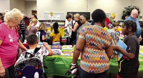 Grandparents helping their grandchildren choose books from the book fair at Turner Woods Elementary School.