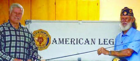 Bill Taylor (left) receives the fishing rod and reel from American Legion Post 142 Commander Russell Curry won in this year’s raffle.