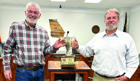 Board of Commissioners Chairman Chris Weidner (left) and Commissioner Sam Kitchens share the March 28 Clean Up trophy at the conclusion of last week’s county commission meeting. DEBBIE LURIE-SMITH/Staff