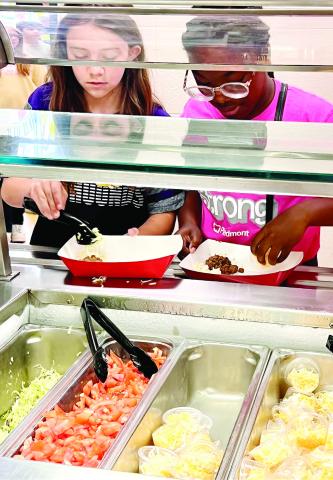 Two students at Gray Station Middle School select what they want in their chipotle bowl from the cafeteria. ALAINA CLARKE/Staff